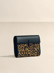 Handbag with leopard print and black leather accents on a beige background