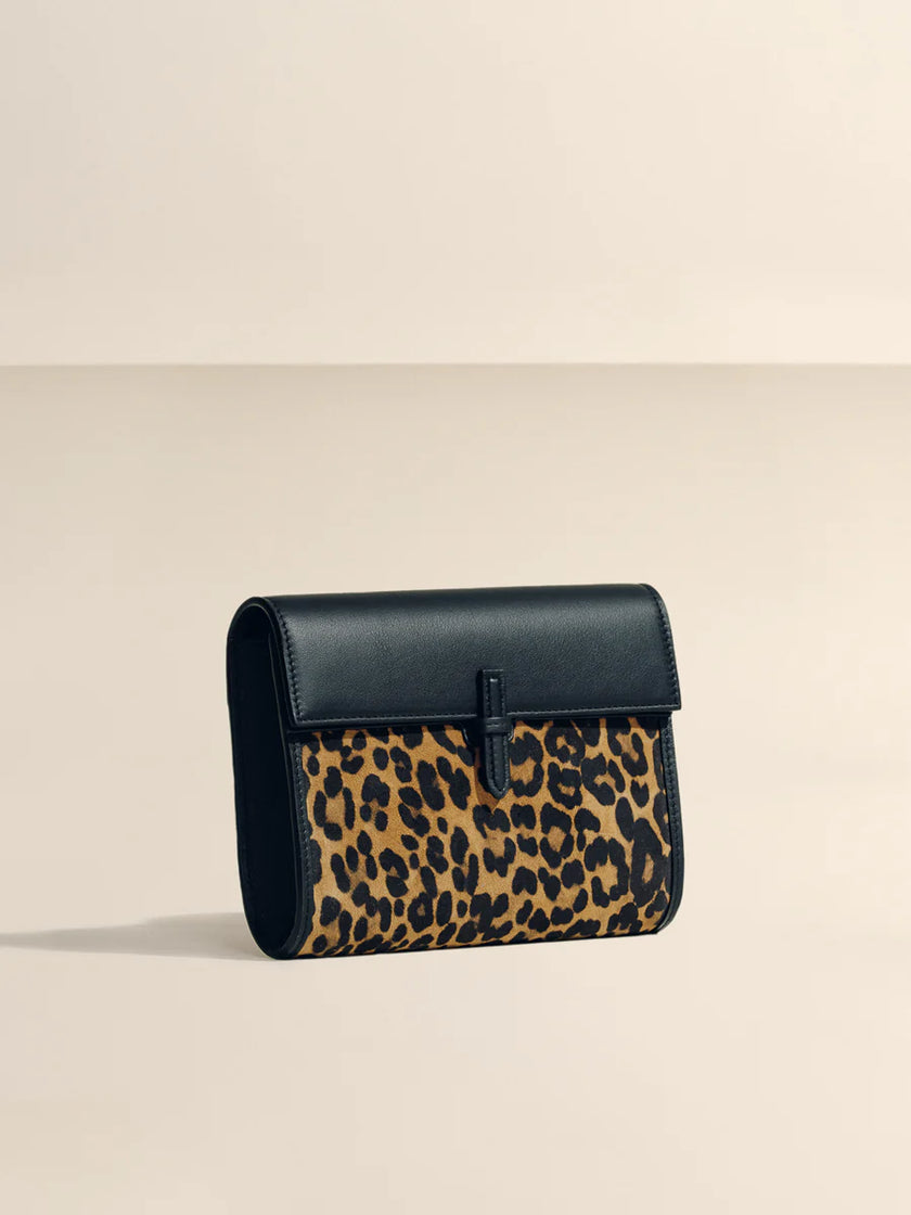 Handbag with leopard print and black leather accents on a beige background