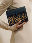 Leopard print clutch held by a person wearing a beige coat