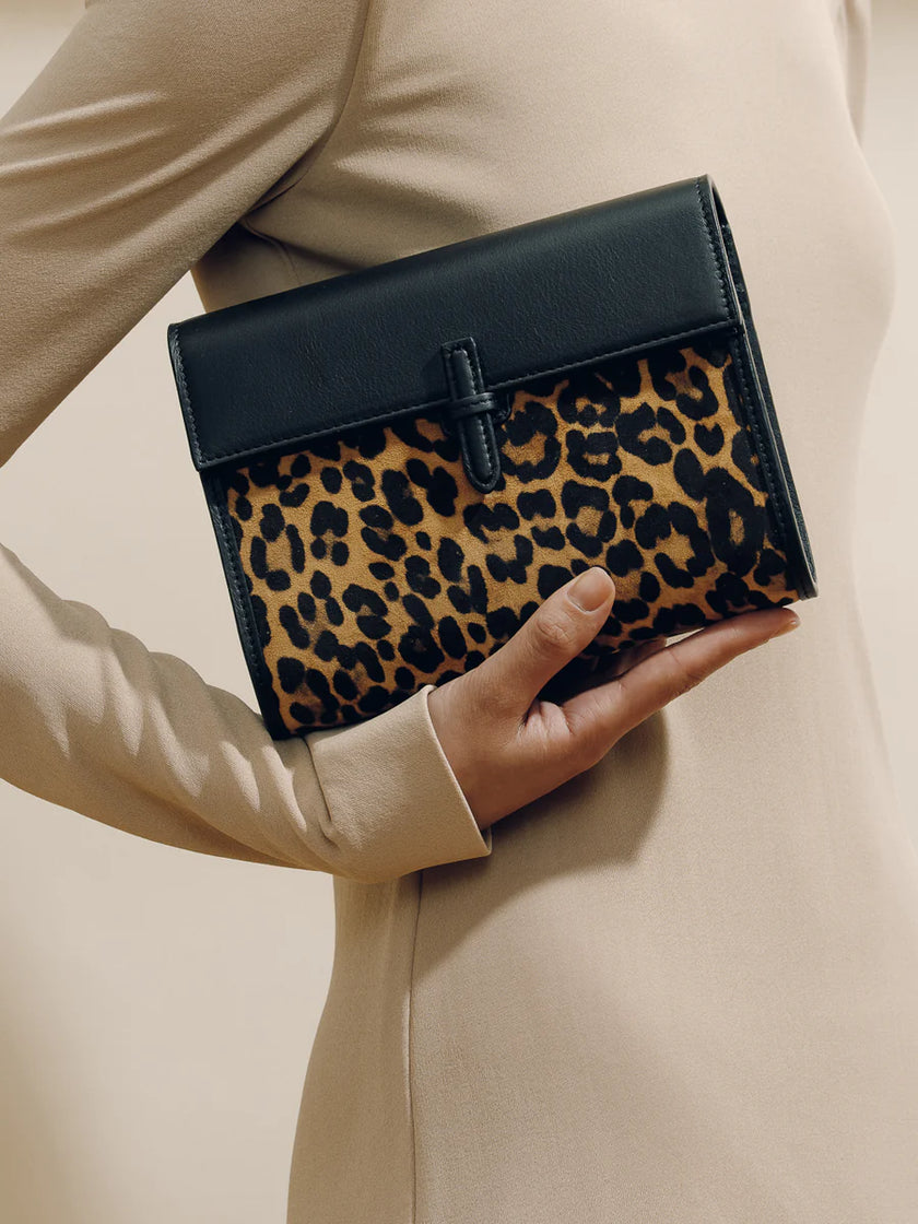 Leopard print clutch held by a person wearing a beige coat