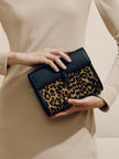 Person holding a black clutch with leopard print design