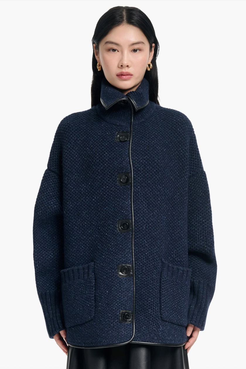 Person wearing a dark blue coat with buttons on a white background