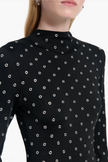 Black long-sleeve top with white polka dot pattern on a white background